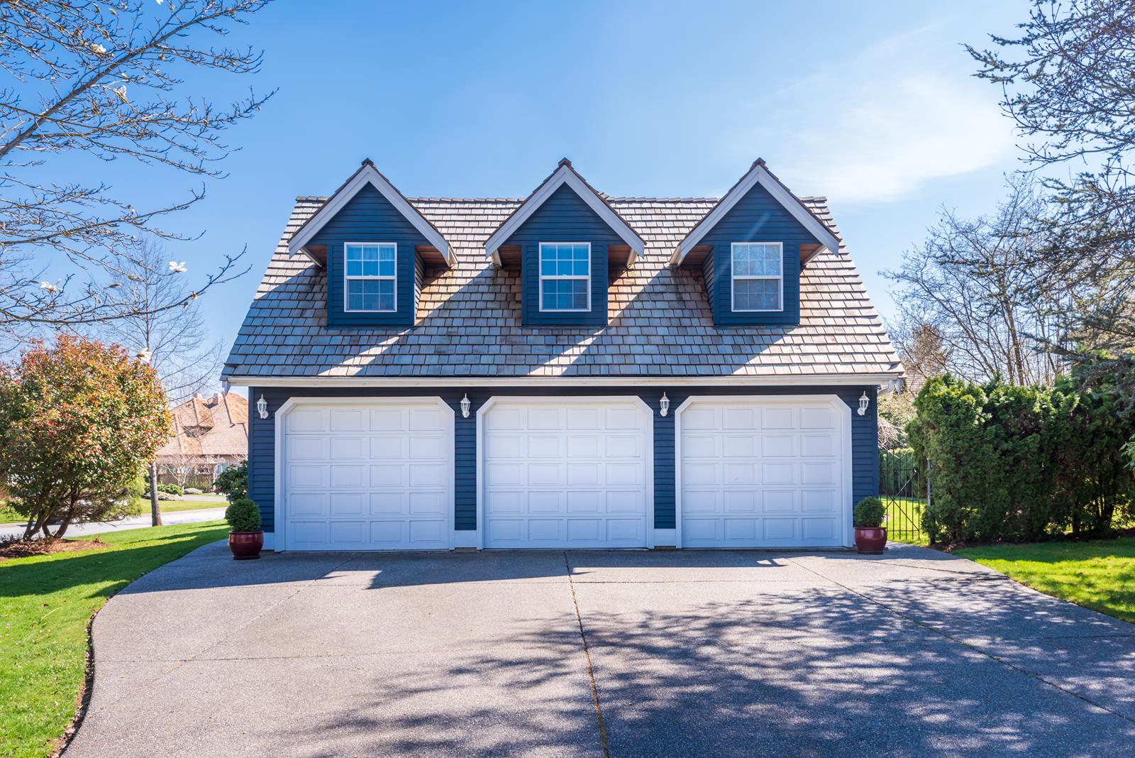 A blue garage with three windows and three doors, exemplifying quality craftsmanship in garage construction and design.
